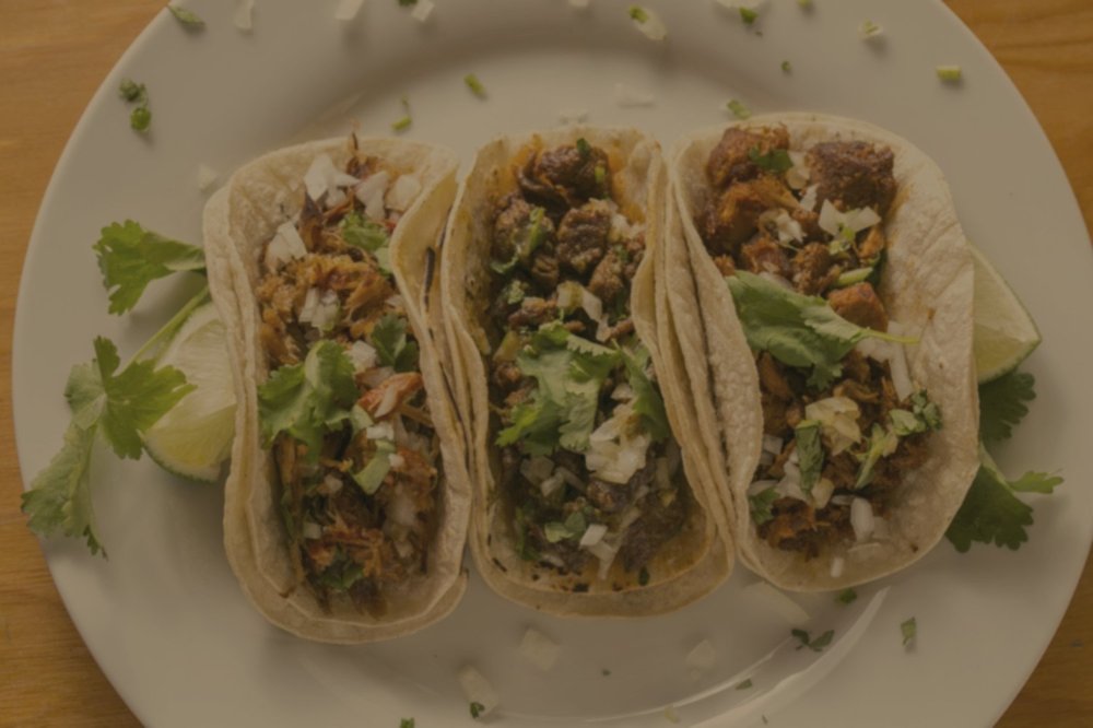 Foto original de tres tacos en un plato blanco, oscura y con tono amarillento